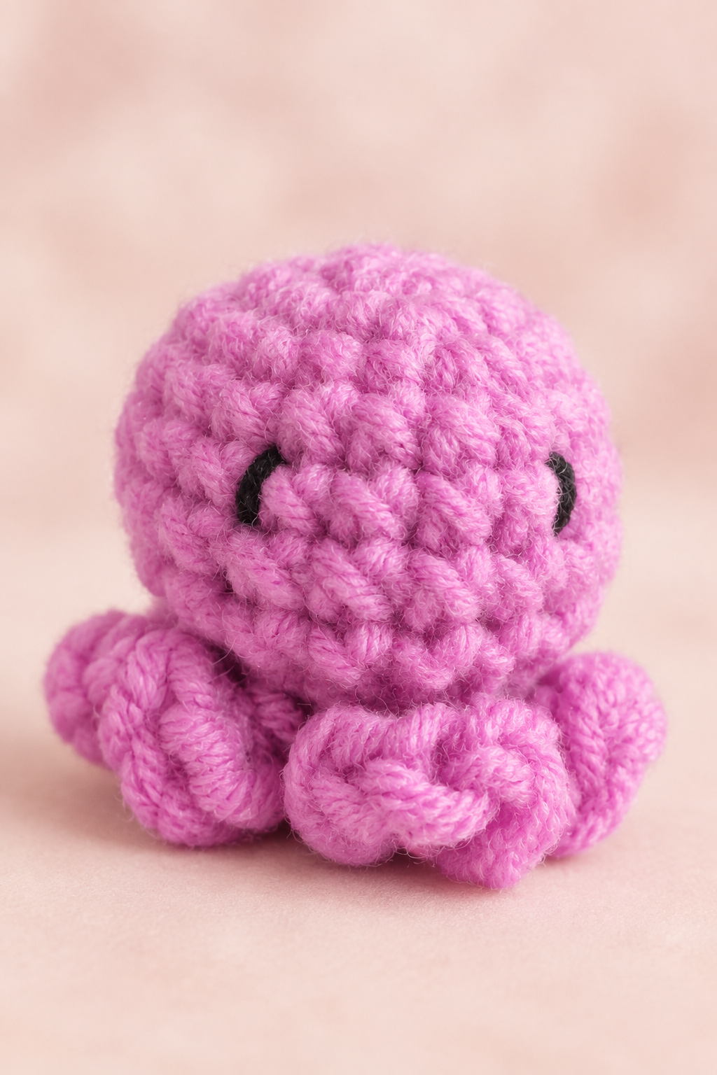 Pink crocheted octopus plush with soft studio background