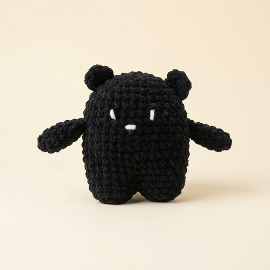 Original black crochet bear with stitched white face on an ivory background