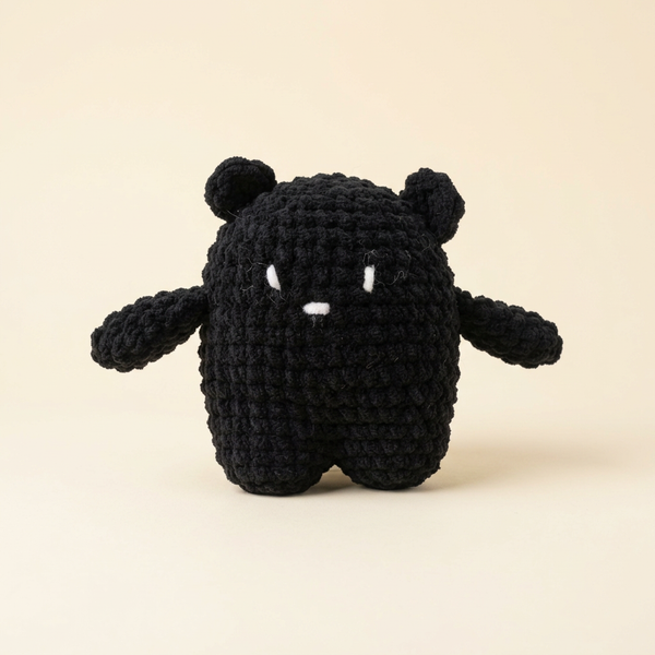 Original black crochet bear with stitched white face on an ivory background