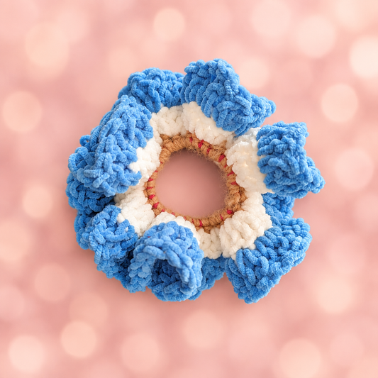 Crocheted blue and white flower hair scrunchie on pink background